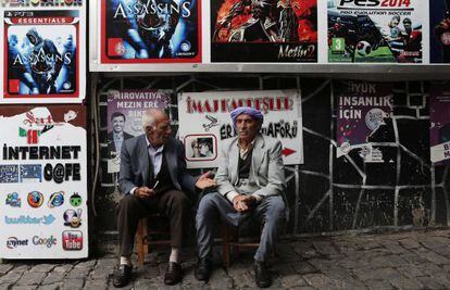 Dos hombres charlan frente a una cafeter&iacute;a decorada con carteles electorales en Diyarbakir (Turqu&iacute;a), el 30 de octubre de 2015. 