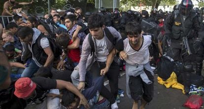 La policía empuja a migrantes en la frontera húngara hoy.