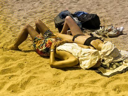 Una pareja toma el sol en una playa de Barcelona