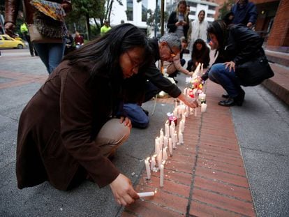 Varias personas encienden velas el d&iacute;a 18 en el centro comercial de Bogot&aacute; atacado la v&iacute;spera. 