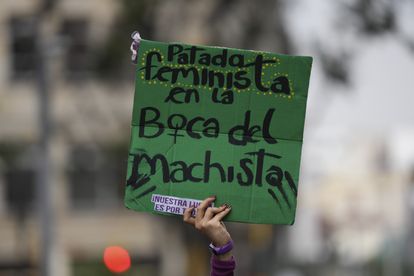 An abortion-rights activist holds a sign that reads in Spanish "Feminist kick on the machista mouth," during a celebration of the anniversary of the Constitutional Court's decriminalization of abortion, lifting all limitations on the procedure until the 24th week of pregnancy, in Bogota, Colombia, Tuesday, Feb. 21, 2023. (AP Photo/Fernando Vergara)