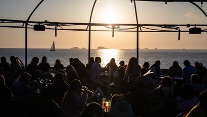 Un grupo de turistas disfrutan de la puesta de sol en una cala de Ibiza.