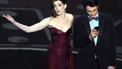 Anne Hathaway mirando al público y James Franco mirando al móvil mientras presentaban la gala de los Premios Oscar del año 2011, una de las que peores críticas ha recibido en los últimos años.