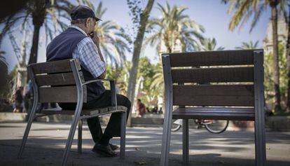 Un señor mayor descansa en un banco en la calle, en Barcelona.