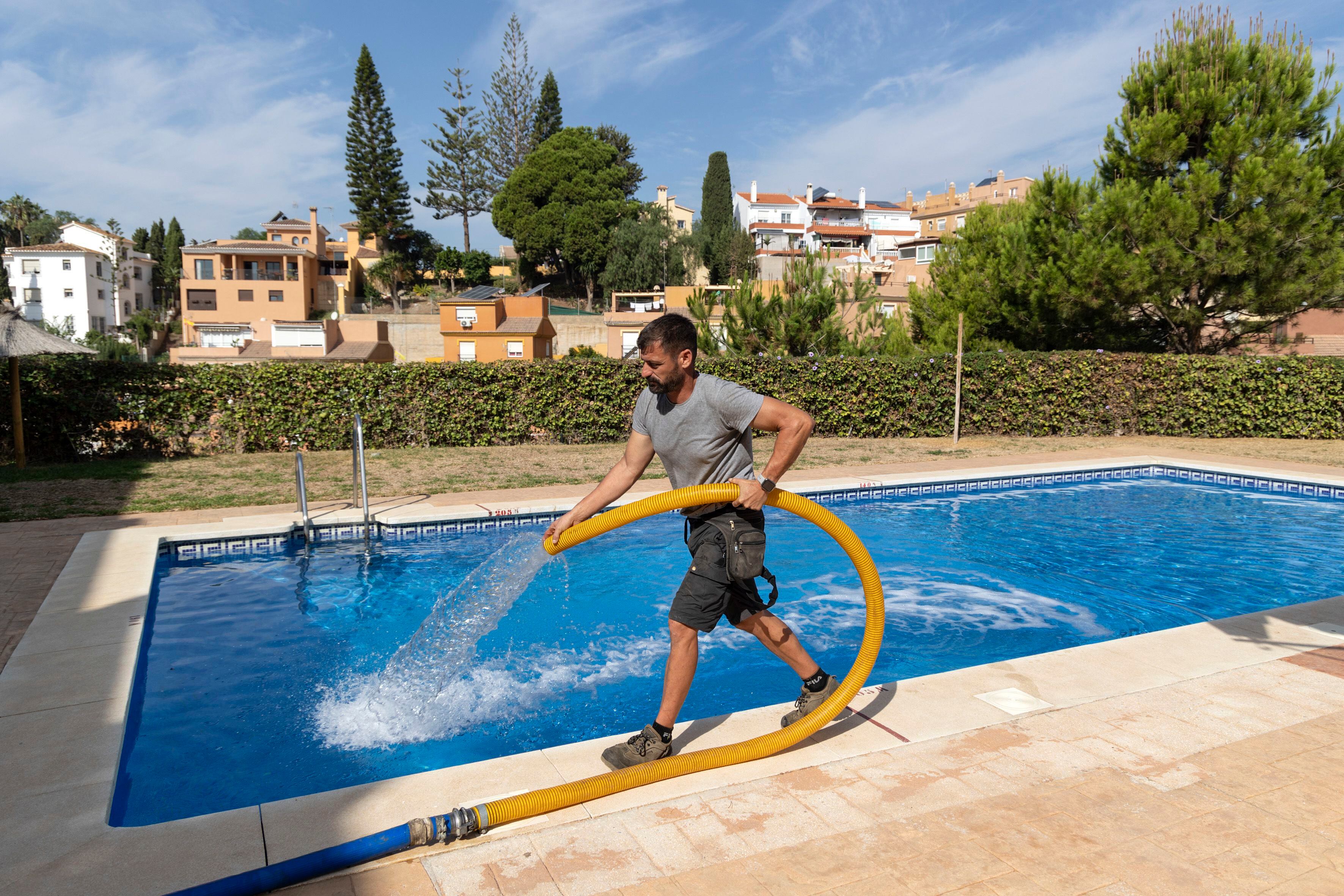Un operario de una empresa de camiones cisterna rellena hace unos días la piscina de una urbanización de la localidad de Rincón de la Victoria (Málaga). 