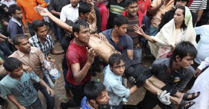 Un grupo de personas carga con un herido en el incendio de una f&aacute;brica textil en las cercan&iacute;as de Daca, Bangladesh. 