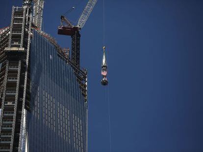 Una gr&uacute;a sube la bandera de EE UU a la cima del One World Trade Center.
 