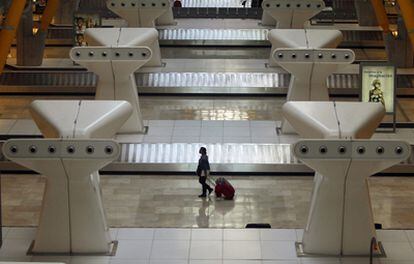 Una pasajera camina el día de la huelga general por la vacía sala donde están las cintas de equipaje de la terminal 4 de Barajas.
