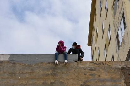Dos niños sentados sobre un muro en la nave de primera acogida del polígono del Tarajal, a 20 de mayo de 2021, en Ceuta (España). Durante los últimos tres días Ceuta ha recibido 8.000 ciudadanos marroquíes, de los cuales 5.600 ya han sido expulsados o retornados voluntariamente al Reino alauita.