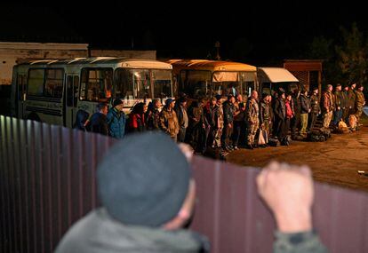 Un hombre observa a un grupo de reservistas reclutados en Rusia para la guerra de Ucrania.