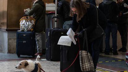 Una mujer con un perro, firmando una declaración de su motivo para viajar en la estación de tren Milano Centrale, el día 10.