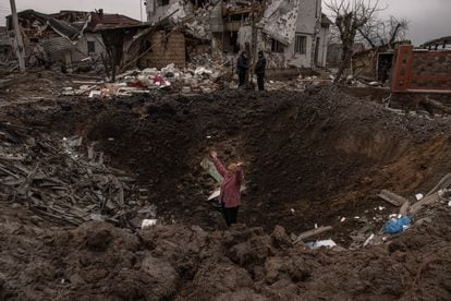 Una mujer en uno de los cráteres provocados por los misiles rusos en Hlevakha, a unos 30 kilómetros de Kiev, este jueves.