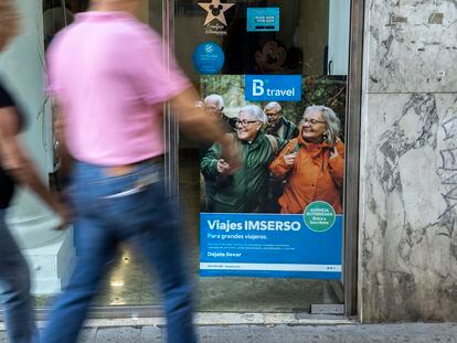 Dos personas pasan delante de un cartel de una agencia autorizada para vender viajes del Imserso.