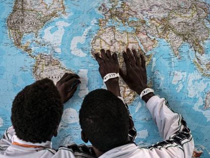 Dos menores de Gambia solicitantes de asilo en Italia, discuten sobre el viaje que han realizado en un mapa en el puerto de Pozzallo, Sicilia.