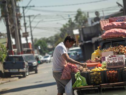 Un vendedor de frutas y verduras selecciona unas papas en su camioneta donde vende directo en los domicilios de las poblaciones de La Pintana, Chile.
