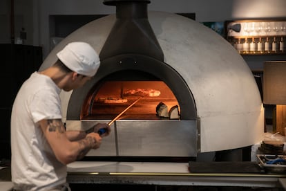 Il pizzaiolo inforna la pizza alla Sartoria Panatieri.