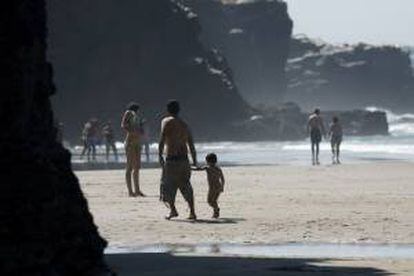 Varias personas pasean bajo el sol en la playa de las Catedrales de Lugo. EFE/Archivo