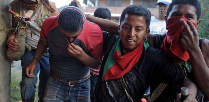 Un grupo de indígenas lleva detenido a un supuesto miembro de las FARC al que capturaron en Belén, en el Cauca, el miércoles.