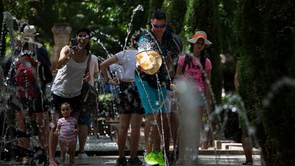 Varios turistas se refrescan en las fuentes cercanas al Palacio de la Almudaina, en Palma de Mallorca, este martes.