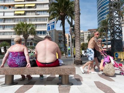 Dos turistas sentados en un banco del paseo marítimo de Benidorm, Alicante.