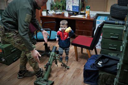 The son of a commander of the Azov Battalion in an arms store next to a militiaman at a base of this movement in kyiv.