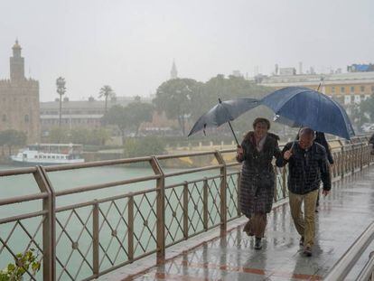 Peatones cruzan bajo la lluvia el puente de los Remedios en Sevilla, el pasado día 22.