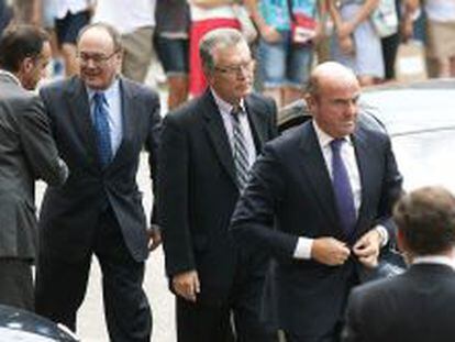 El ministro de Econimia, Luis de Guindos, Luis Mar&iacute;a Linde y Samuel Ruiz, a su llegada al funeral por la muerte del presidente del Banco Santander