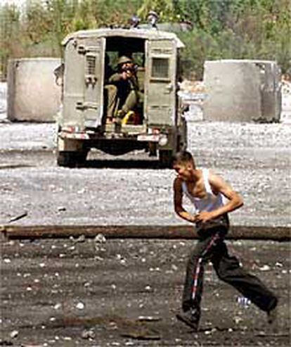 Un joven palestino corre ante un vehículo del Ejército israelí en Ramallah.