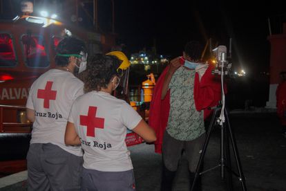 Dos personas de Cruz Roja atienden a un joven llegado en patera al puerto de Motril el pasado 10 de agosto.