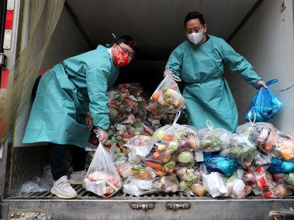 Trabajadores con equipo protector reparten bolsas de alimentos a los habitantes de un complejo residencial durante el confinamiento de Shanghái, este martes.