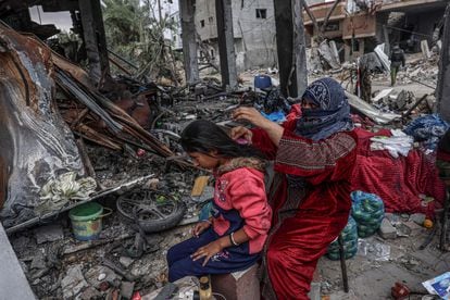 Una mujer palestina cepilla el pelo a una niña, junto algunas de las pertenencias que han podido recuperar entre la destrucción, en la ciudad de Khuzaa, cerca de Jan Yunis, este lunes.  