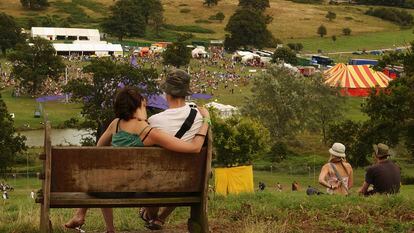 Dos jóvenes miran desde lejos algunas de las carpas en un festival de música al aire libre.