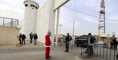 Un manifestante disfrazado de Pap&aacute; Noel, ante el muro de separaci&oacute;n en Bel&eacute;n.