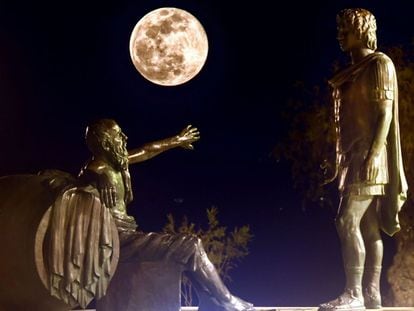 La 'superluna de nieve' se alza entre las estatuas de Alejandro Magno (a la derecha) y Diógenes de Sínope, en Corinto (Grecia).