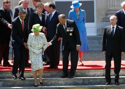 Barack Obama ayuda a la reina Isabel II a bajar las escaleras, antes de posar para la foto de familia durante los actos del 70 aniversario del Día D en Normandía, en presencia del presidente ruso, Vladimir Putin.
