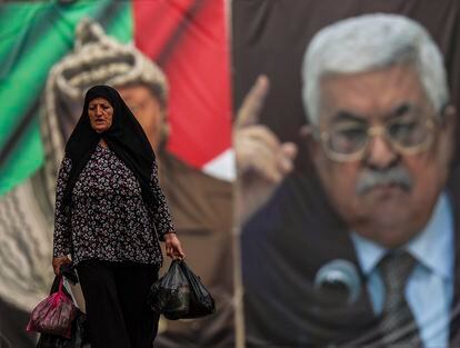 Un a mujer pasa delante de un cartel con las imágenes de Yaser Arafat y de Mahmud Abbás en la Plaza del Pesebre de Belén, Cisjordania. 