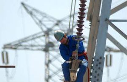 Un trabajador instala nuevas líneas de alto voltaje en una torre de electricidad.