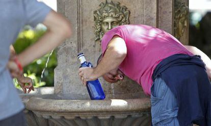 Un turista se refresca en una fuente de Valencia. 