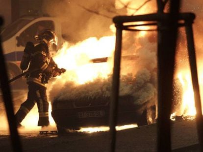 Un bombero intenta apagar el incendio en un coche en Nochevieja en Estrasburgo. 