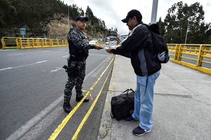 Un policía ecuatoriano comprueba la identificación de un migrante venezolano en el puente de Rumichaca en Tulcán (Ecuador).