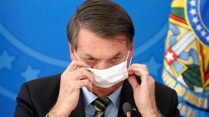 El presidente Bolsonaro se ajusta la mascarilla, durante un acto en Brasilia. / REUTERS