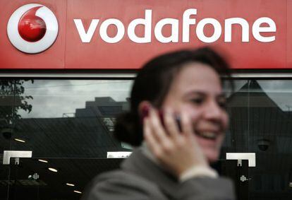 Una mujer habla por tel&eacute;fono mientras pasa ante una tienda Vodafone.