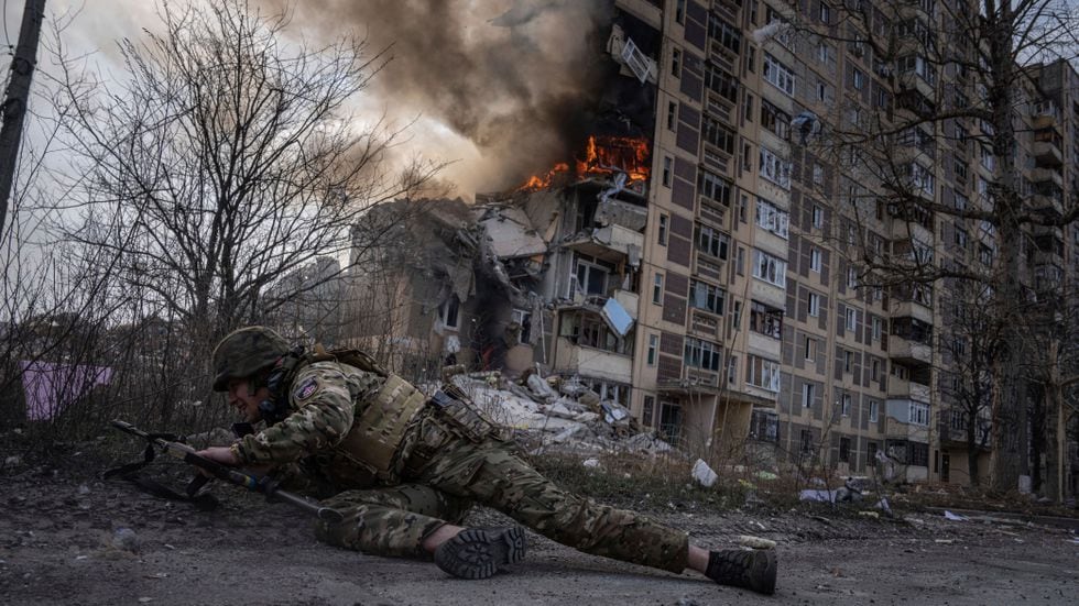 Un soldado ucranio se pone a cubierto junto a un edificio en llamas por un ataque aéreoruso en Avdiivka, en el este de Ucrania, el 17 de marzo. 