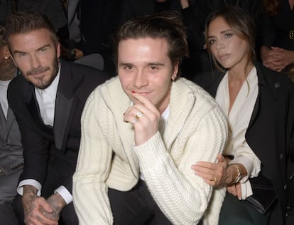 Brooklyn Beckham, escoltado por sus padres David y Victoria en un desfile de Dior Homme Menswear en París en enero de 2020.