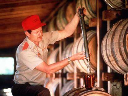 Un trabajador de la destilería estadounidense llena directamente del barril una botella de <i>whisky.</i>