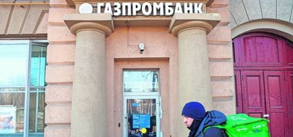 Un repartidor de comida a domicilio pasa con su bicicleta junto a una oficina de Gazprombank, en Moscú.