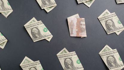 Un billete de 5.000 colombianos entre dólares americanos, en una fotografía ilustrativa.