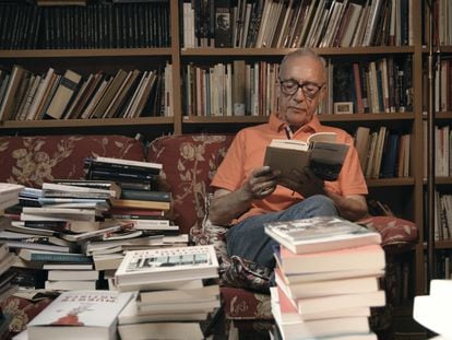 El escritor Juan José Millás leyendo entre las montañas de libros que configuran su biblioteca, antes de la entrevista.