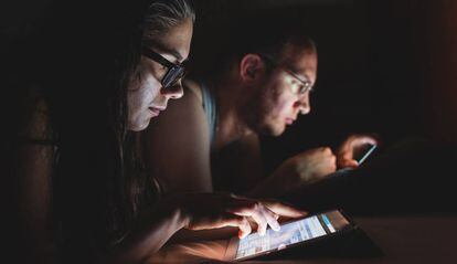 Una pareja lee en sus dispositivos móviles.