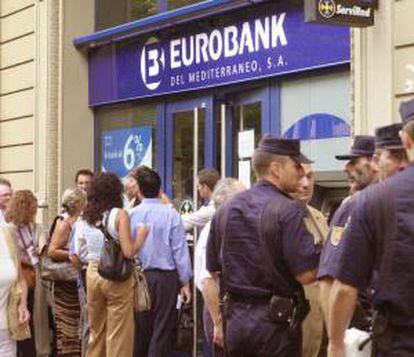 Clientes del Banco Eurobank del Mediterráneo hacen cola en una sucursal en Barcelona para intentar recuperar su dinero e informarse de la situacion de la entidad financiera intervenida por el Banco de España a petición propia por sus problemas patrimoniales. EFE/Archivo